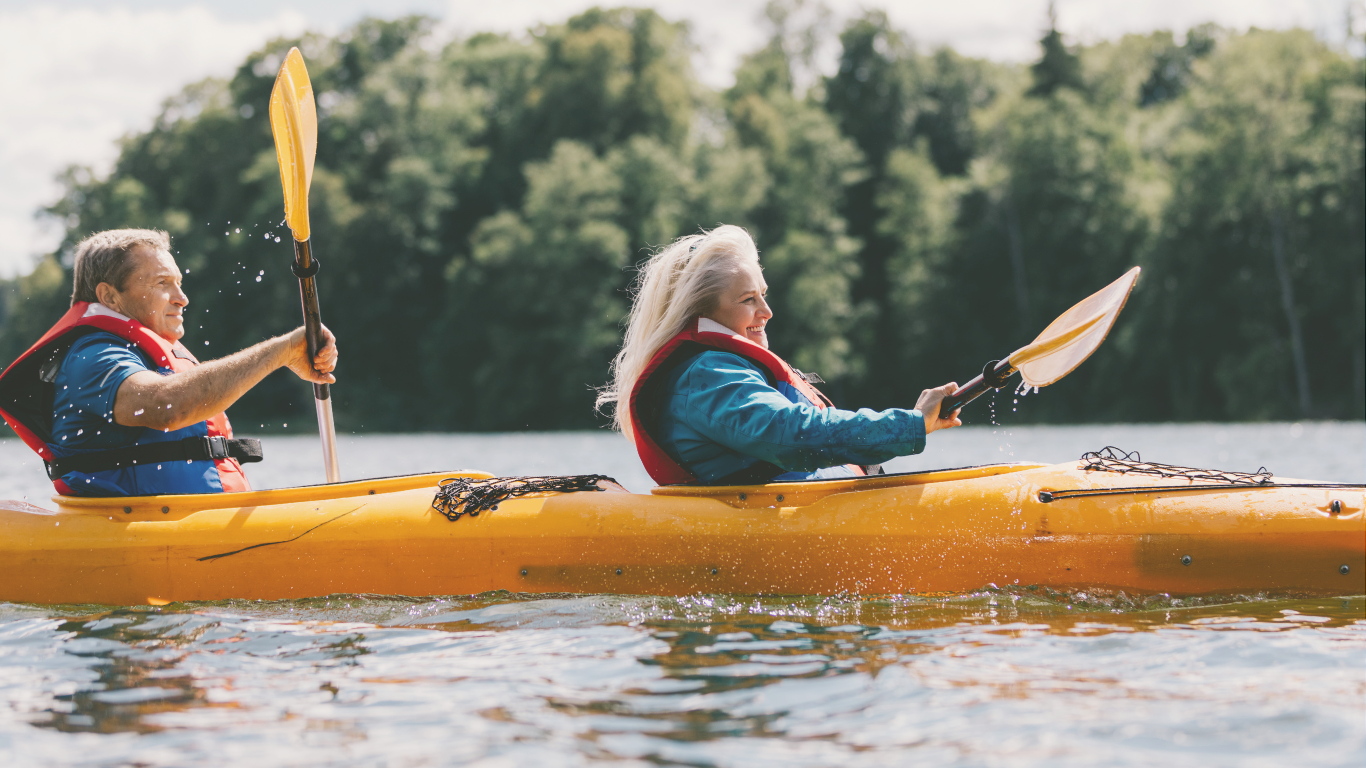 A senior couple kayaking on a lake while traveling full-time in their RV, enjoying adventure and scenic off-grid travel.